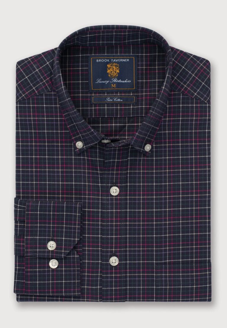 Folded navy and red checkered shirt with a brand label on a light gray background